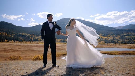 Reia Cho and Rahul Madduluri holding hands with a mountain backdrop during Estes Park wedding portraits